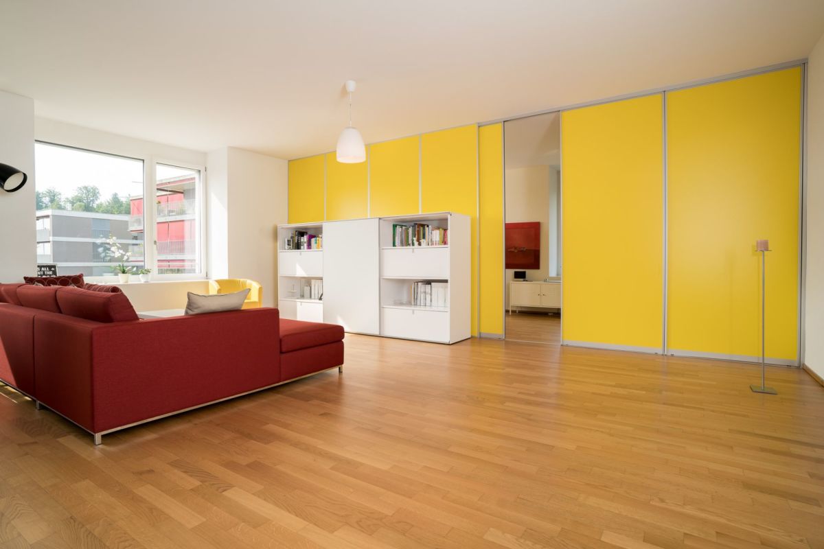 Helles Wohnzimmer mit rotem Sofa und gelben Schrankfronten