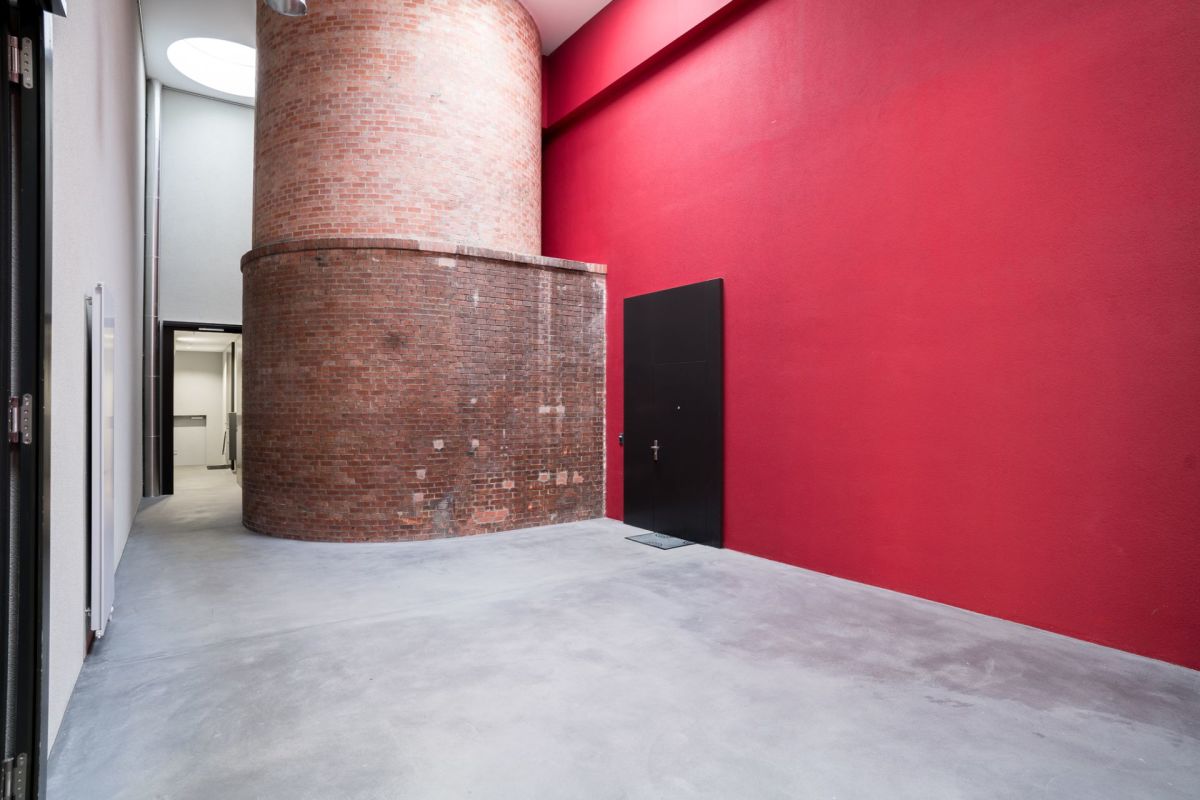 Industrieller Innenraum mit roter Wand und zylindrischem Ziegelkern