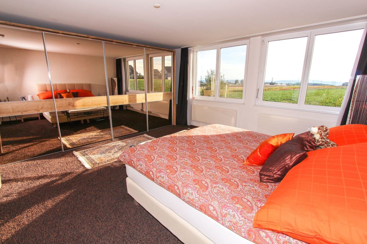 Helles Schlafzimmer mit Spiegelschrank und Landschaftsblick