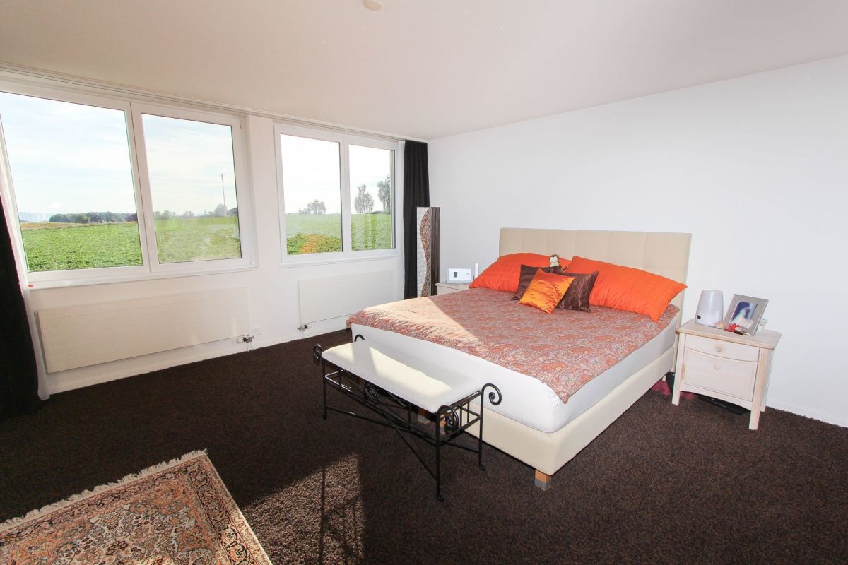 Helles Schlafzimmer mit großem Fensterblick aufs Feld