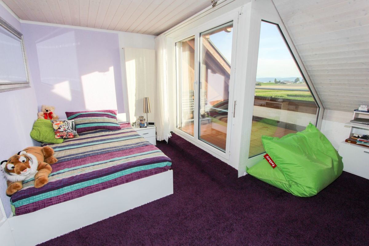 Schlafzimmer unter dem Dach mit großem Fenster und Ausblick