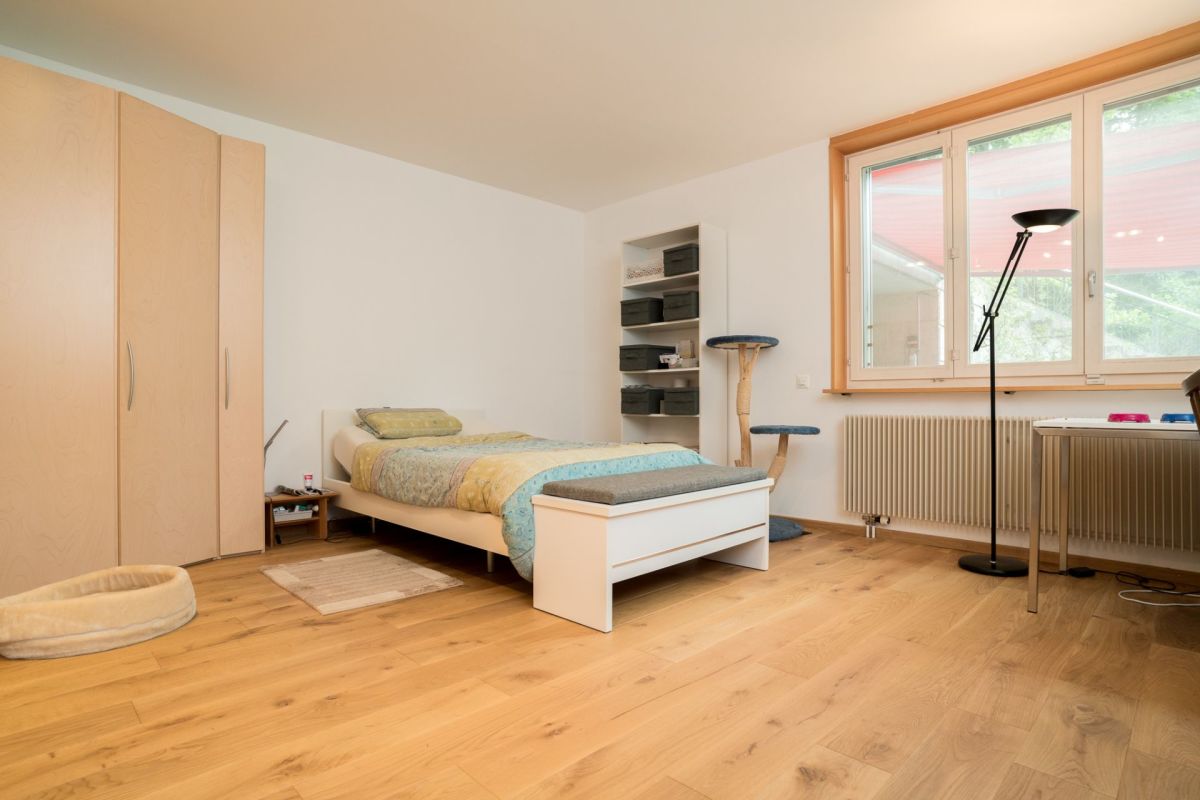 Helles Schlafzimmer mit Holzboden und großem Fenster