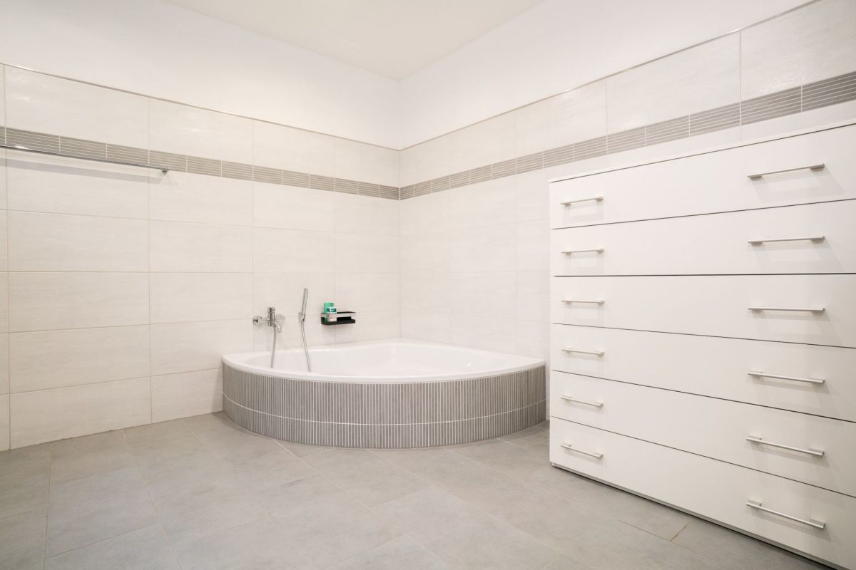 Modernes Badezimmer mit Eckbadewanne und großem Stauraumschrank