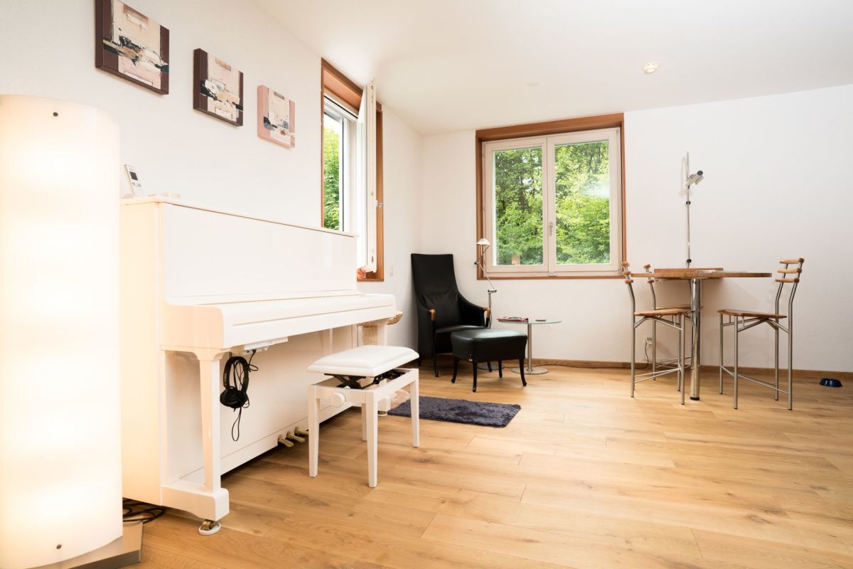 Heller Wohnraum mit Klavier und Sitzgruppe
