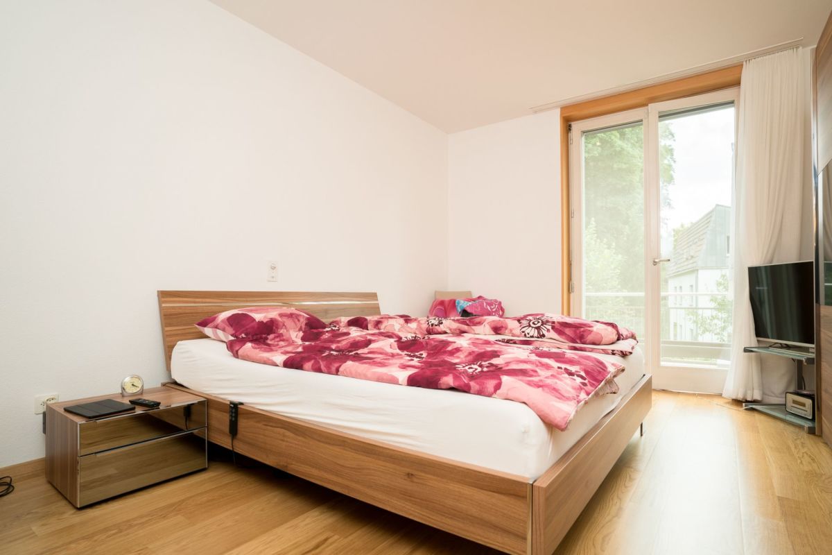 Helles Schlafzimmer mit Holzmöbeln und Balkonfenster