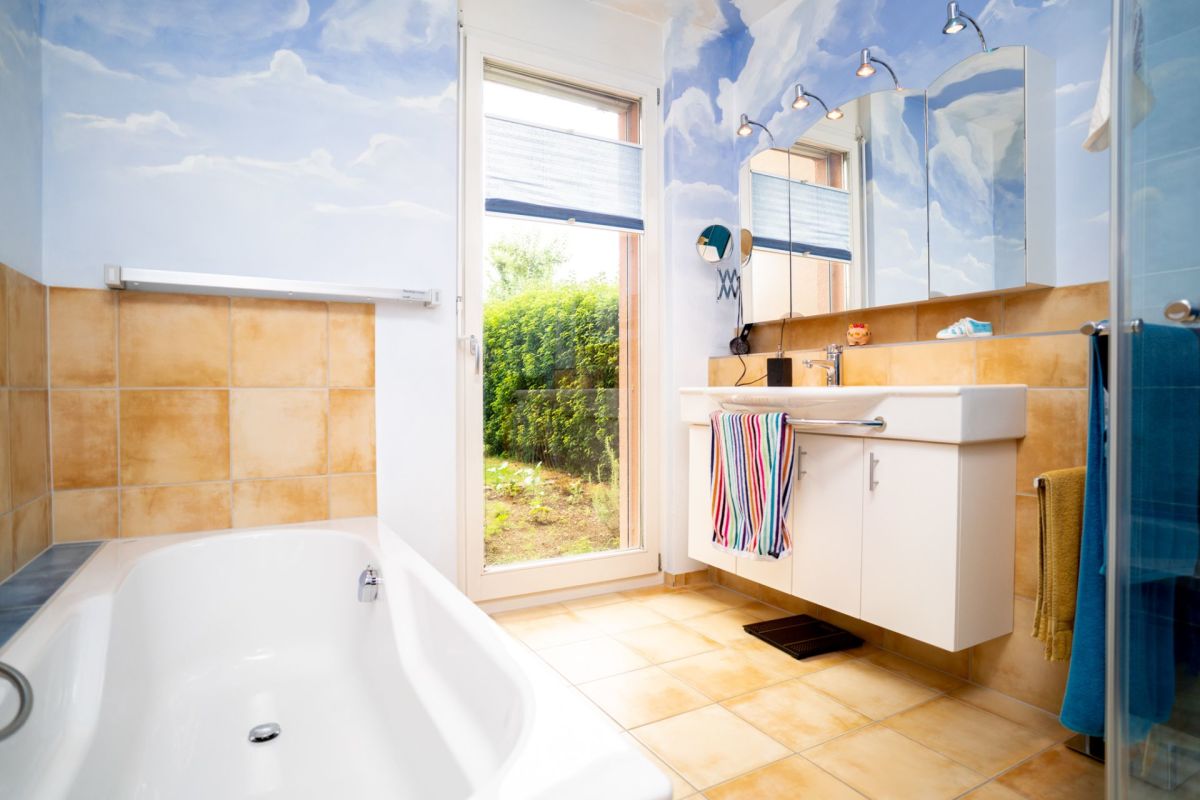 Helles Badezimmer mit Badewanne und Gartenblick