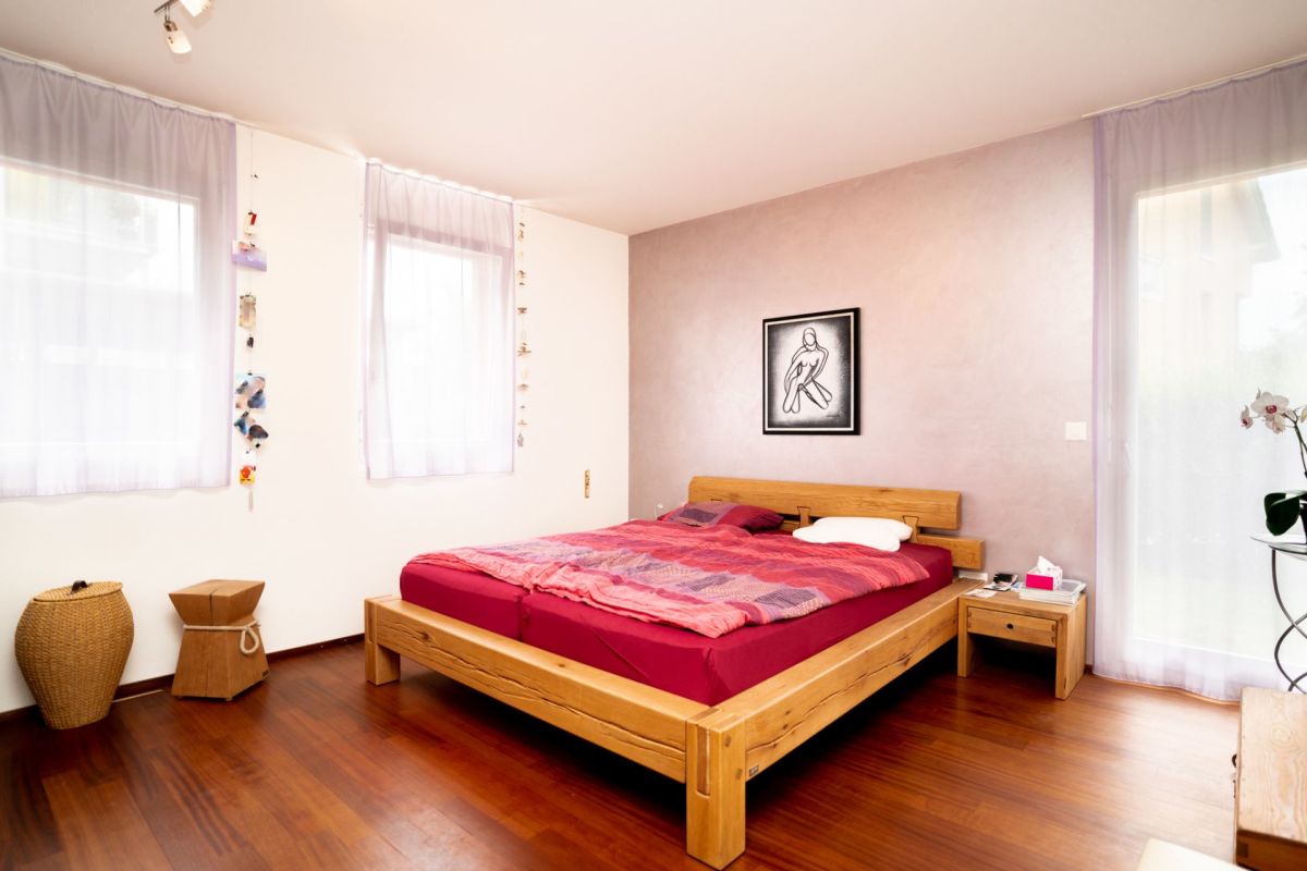 Helles Schlafzimmer mit Holzbett und großen Fenstern
