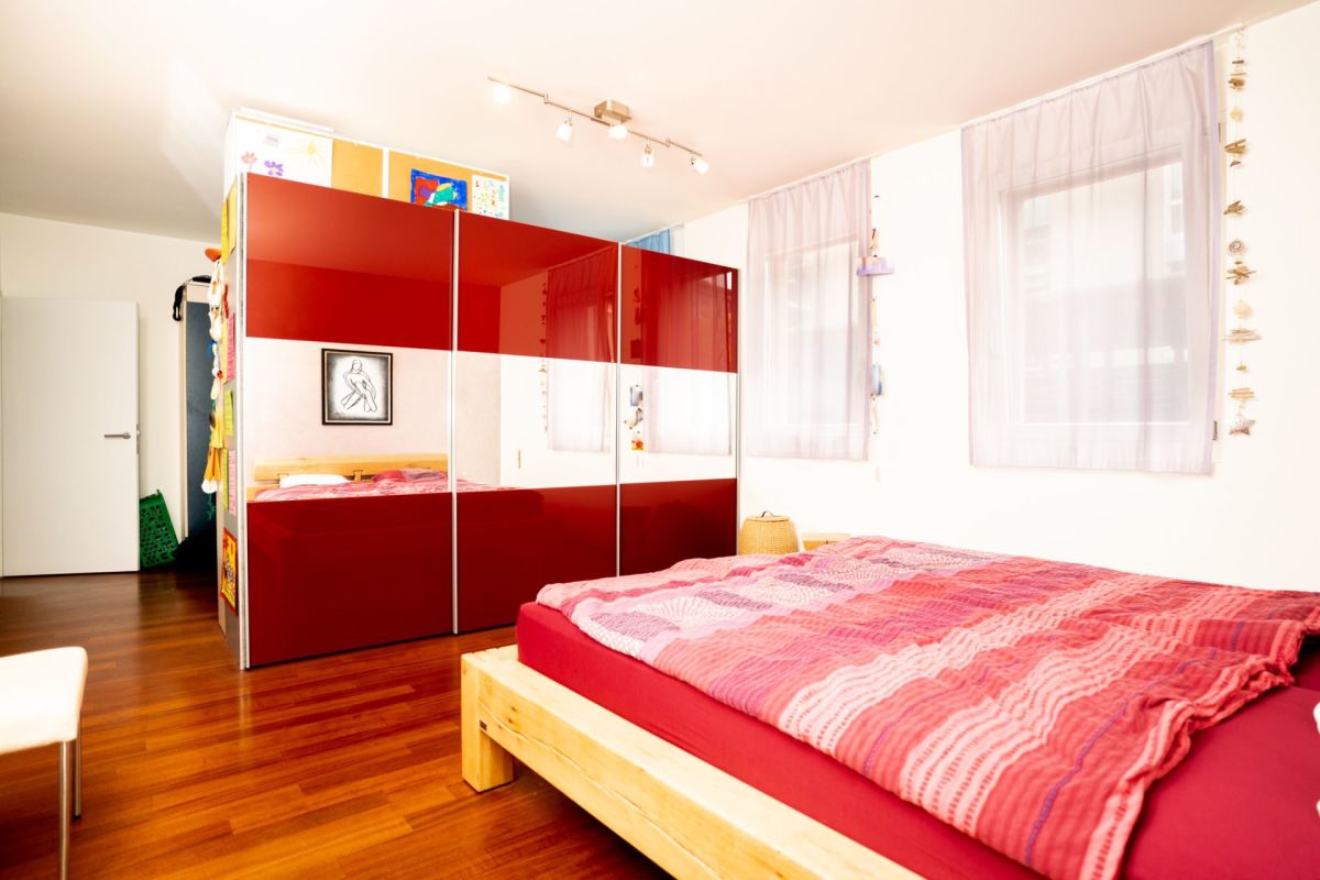 Helles Schlafzimmer mit rotem Kleiderschrank und Holzfußboden