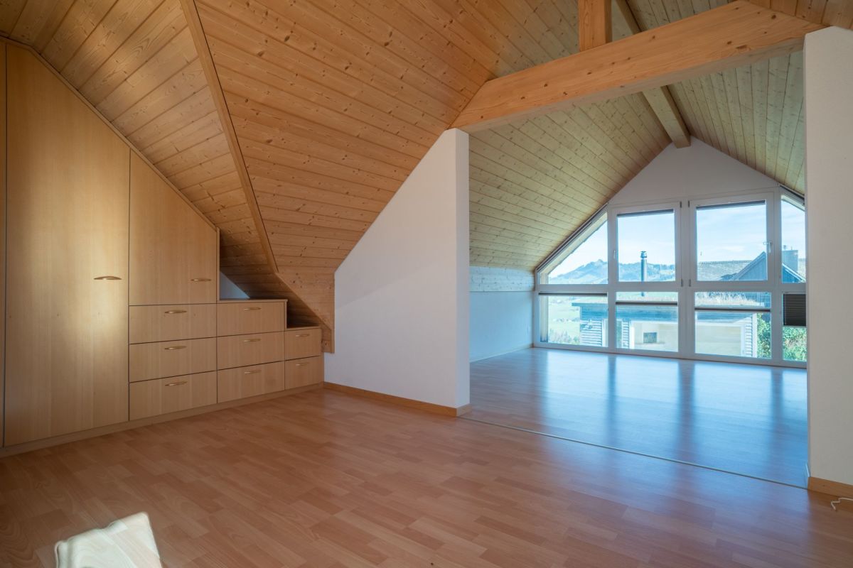 Dachgeschosszimmer mit Holzdecke und Panoramafenster
