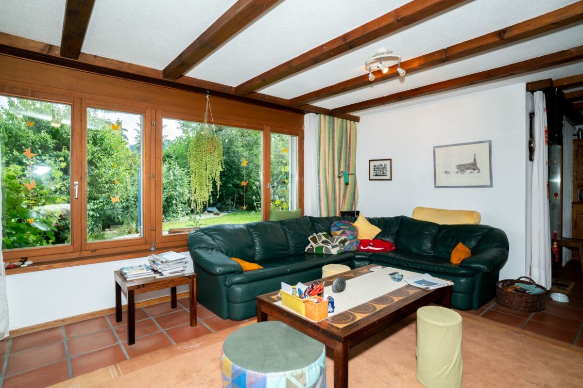Wohnzimmer mit großen Holzfenstern und sichtbaren Deckenbalken