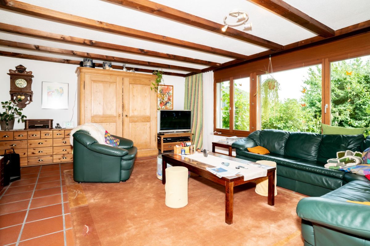 Wohnzimmer mit Holzdeckenbalken und Gartenblick