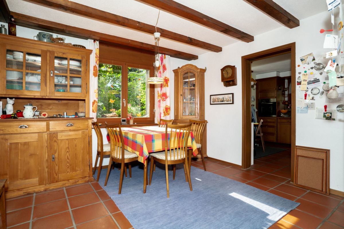 Esszimmer mit Holzvitrine und Blick in die Küche