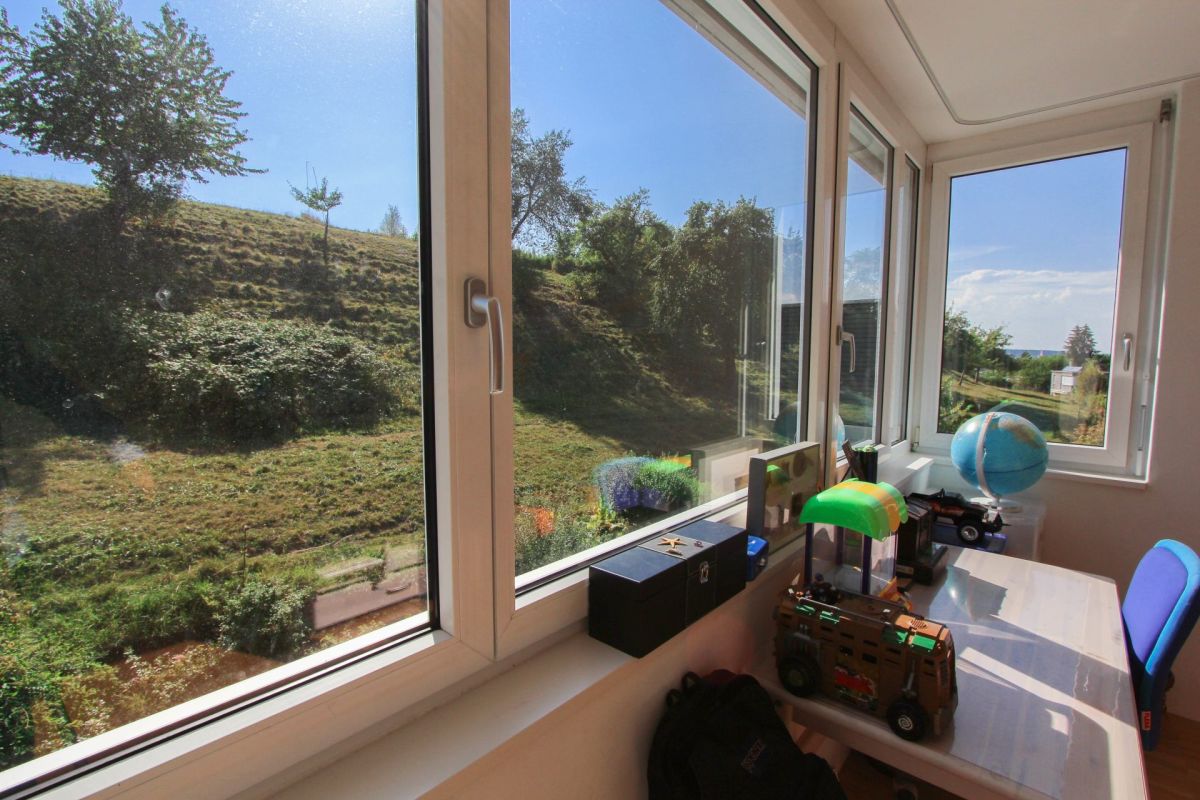 Heller Raum mit großflächigen Fenstern und Grünblick