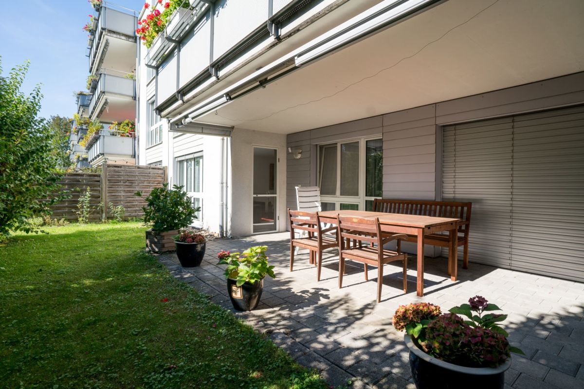 Überdachte Terrasse mit Garten und Wohnhausfassade
