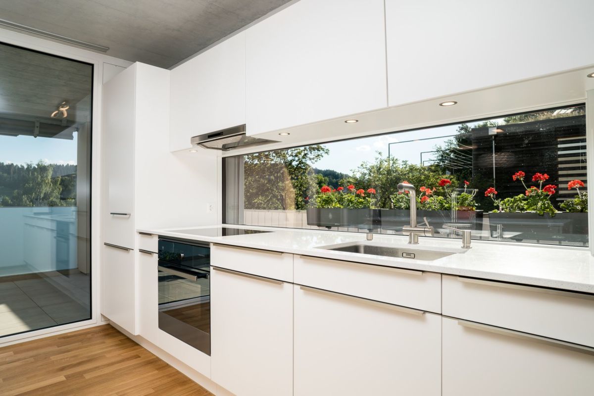 Moderne weiße Küche mit großem Fenster