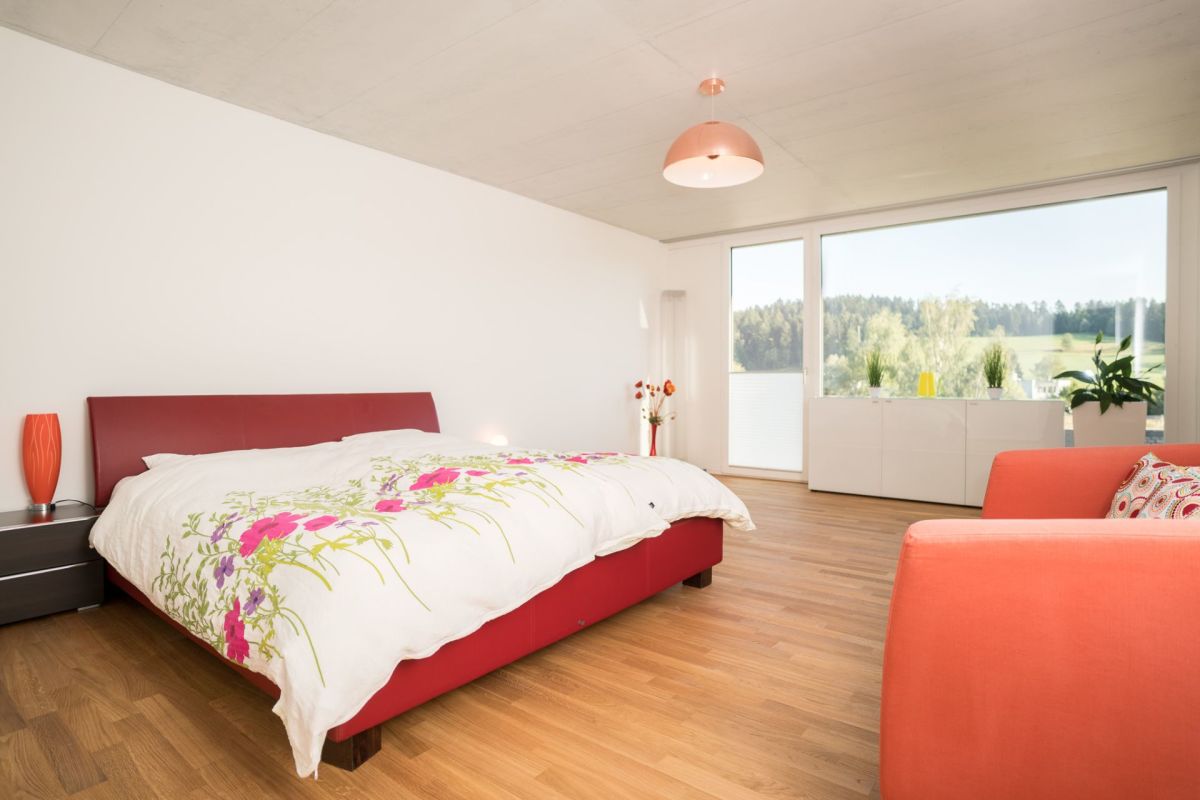 Helles Schlafzimmer mit großem Fenster und Blick ins Grüne