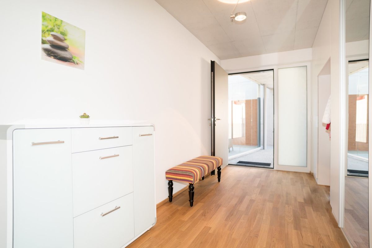 Heller Flur mit Holzoptik-Boden und Eingang zum Außenbereich