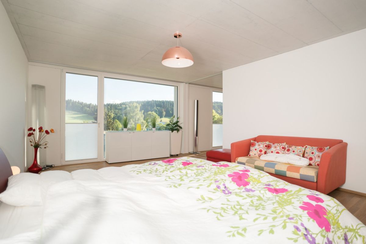 Schlafzimmer mit Panoramafenster und Blick ins Grüne