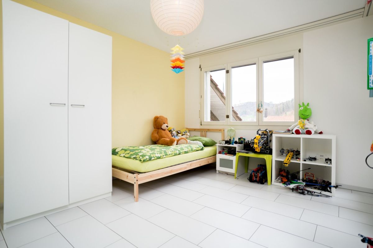 Kinderzimmer mit Bett und weißen Schränken