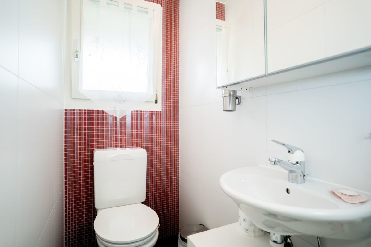 Kleines modernes Gäste-WC mit rotem Mosaikakzent