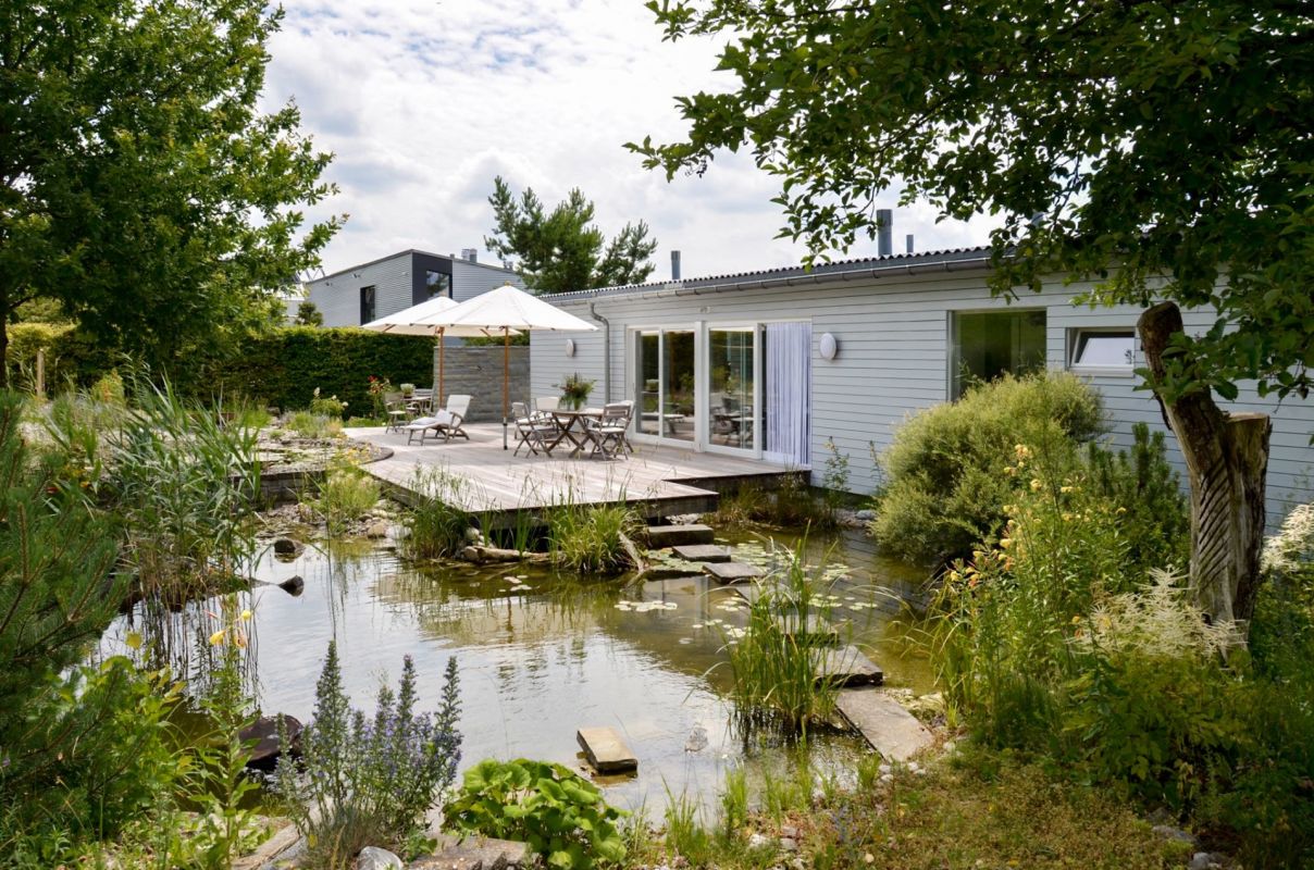 Gartenansicht eines eingeschossigen Hauses mit Terrasse und Teich