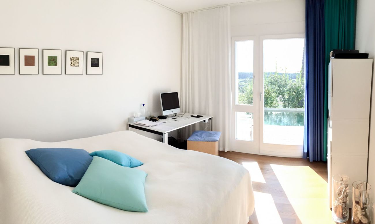 Helles Schlafzimmer mit Arbeitsplatz und Balkonblick