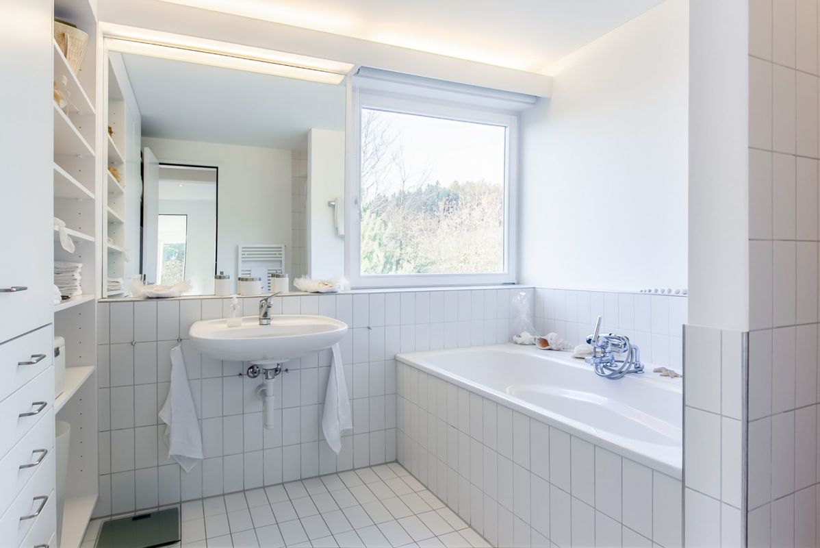 Helles weißes Badezimmer mit Badewanne und Fenster