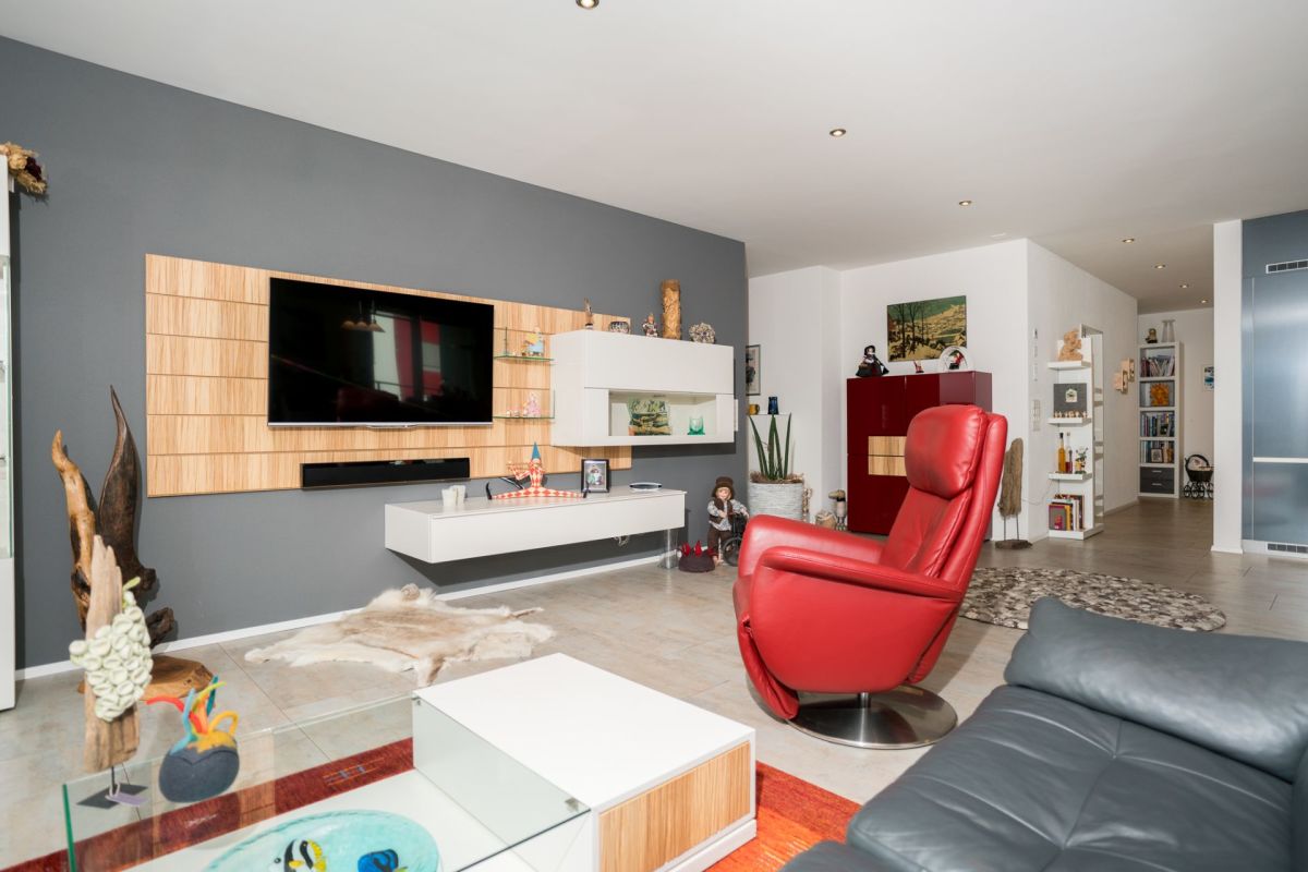 Modernes Wohnzimmer mit TV-Wand und rotem Ledersessel