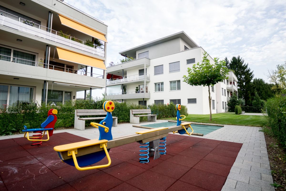 Außenbereich mit Spielplatz zwischen modernen Mehrfamilienhäusern