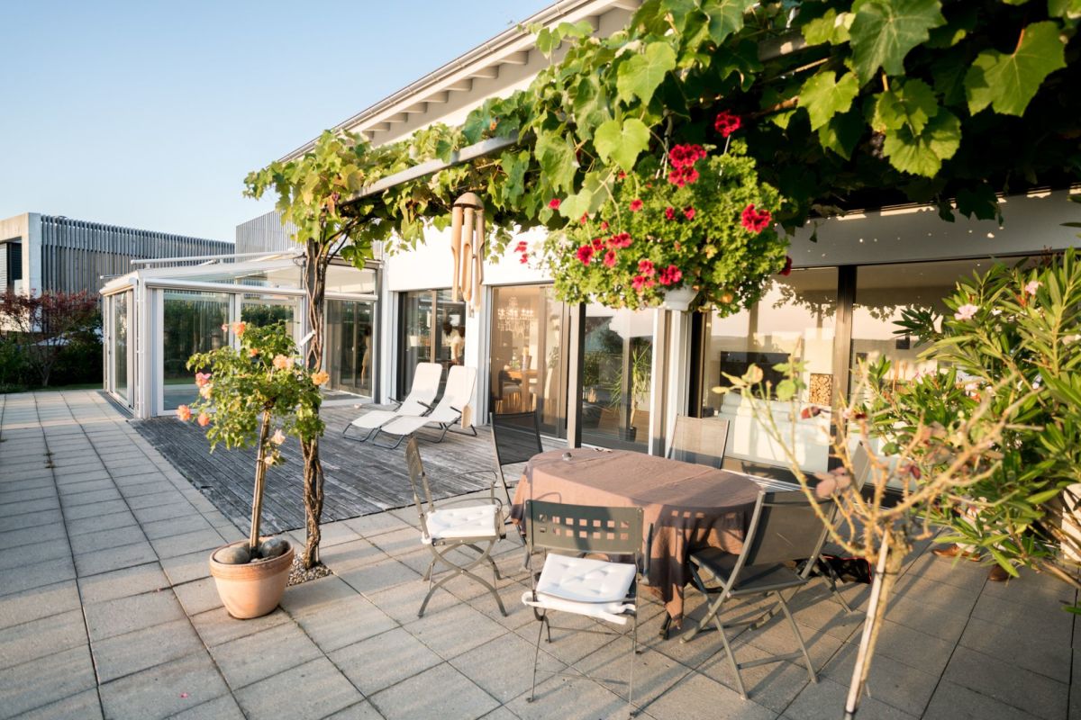 Terrasse mit Glasfront und üppiger Bepflanzung