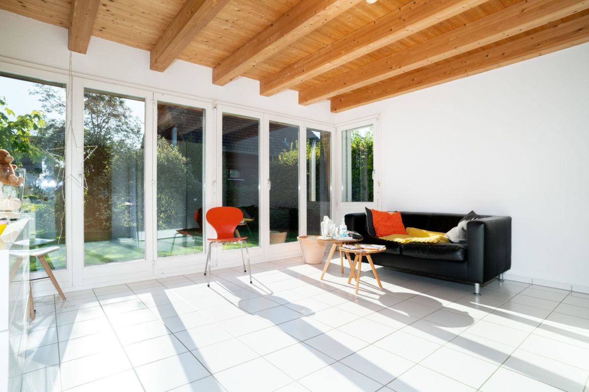 Heller Wohnraum mit Holzdecke und großen Fenstern