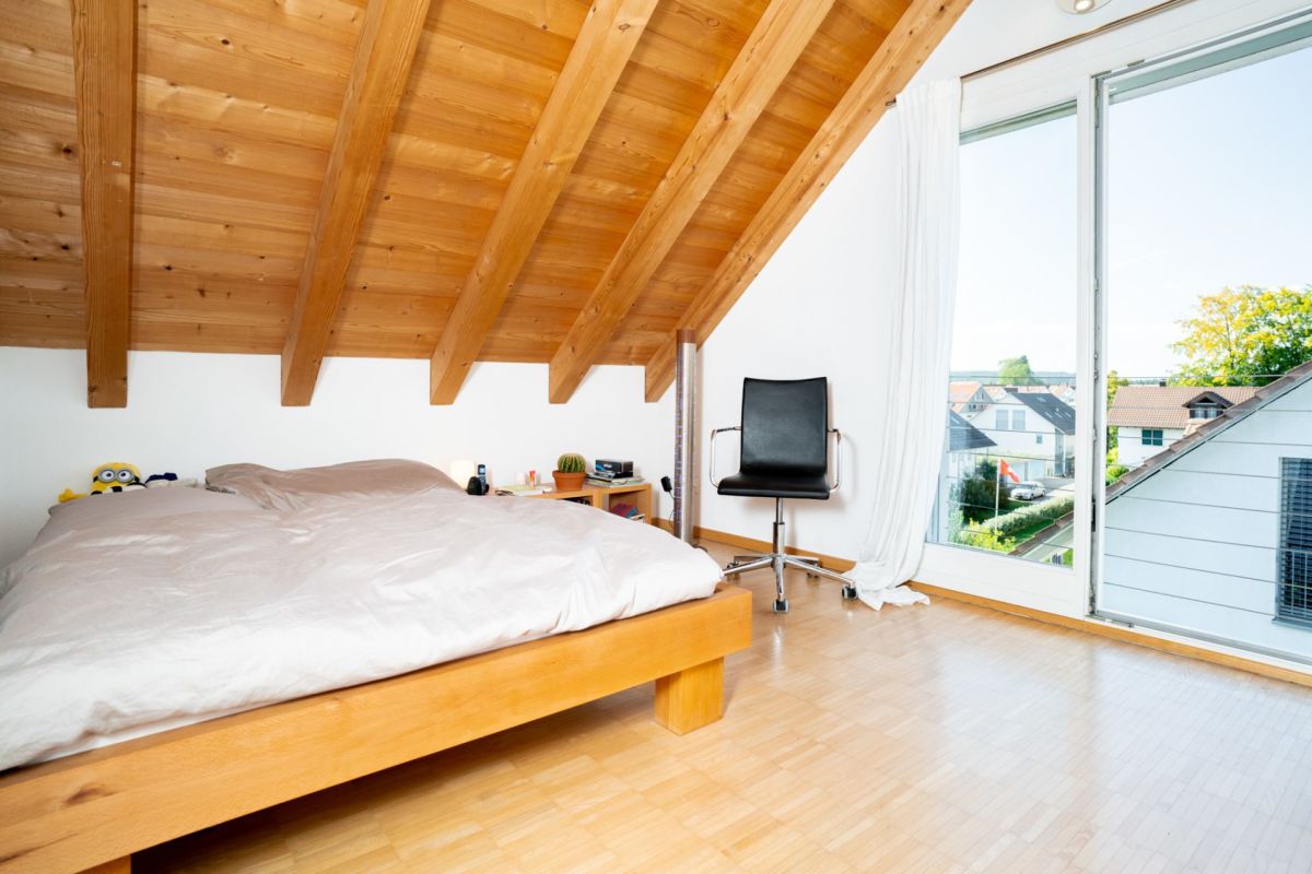 Dachgeschoss-Schlafzimmer mit Holzdecke und großem Fenster