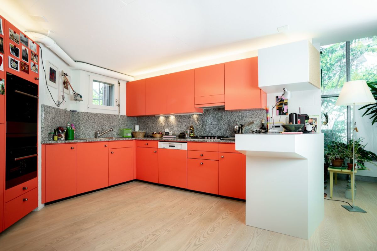 Orangefarbene Wohnküche mit großem Fenster