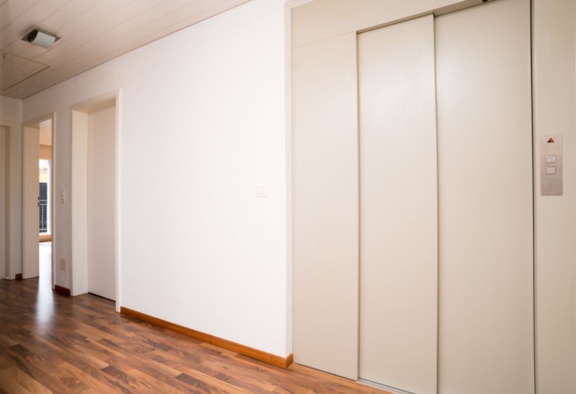 Heller Flur mit Aufzug und Holzboden