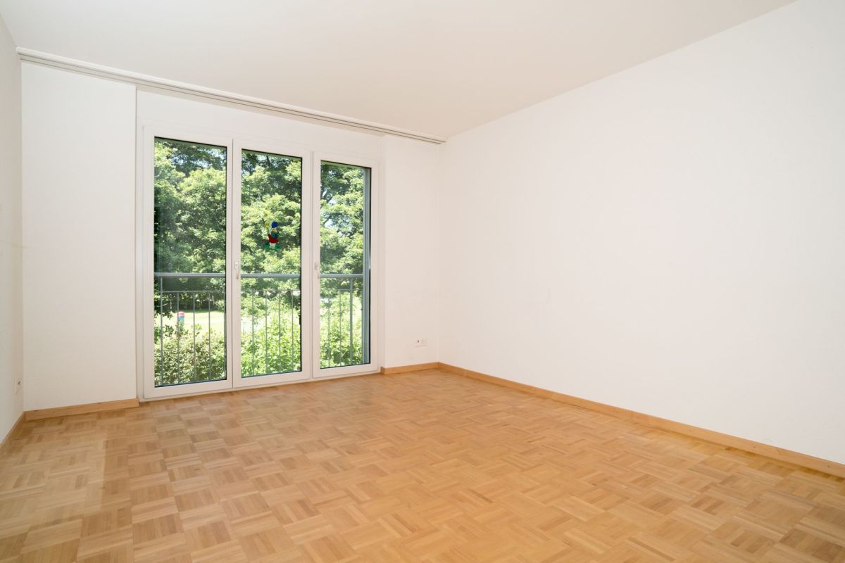 Leerer heller Raum mit Balkon- oder Terrassentür zum Grünblick