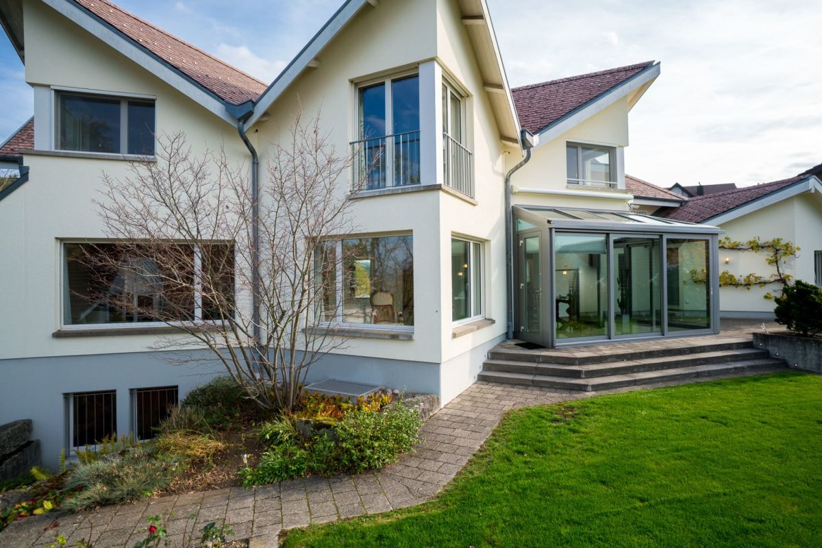 Moderne Hausansicht mit Garten und Wintergarten