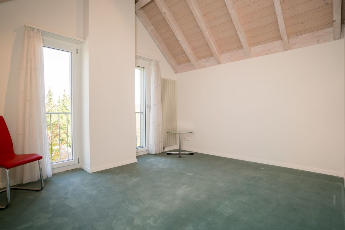Helles Dachzimmer mit Teppich und Sichtbalken