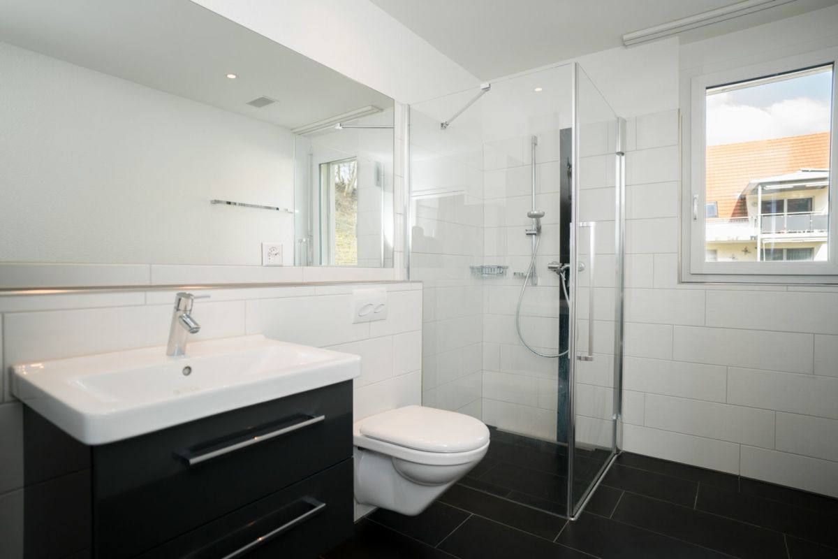 Modernes Badezimmer mit schwarzem Waschtisch und Duschkabine