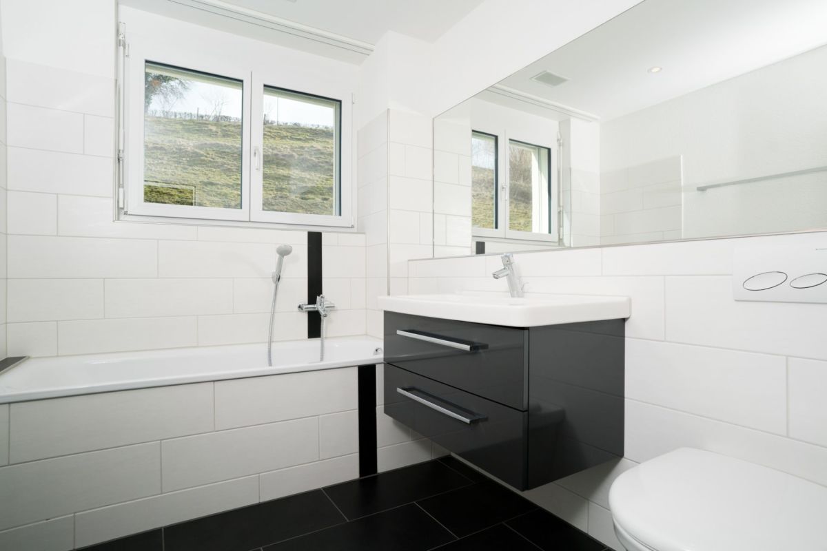 Modernes Badezimmer mit Badewanne, Waschtisch und Fensterblick