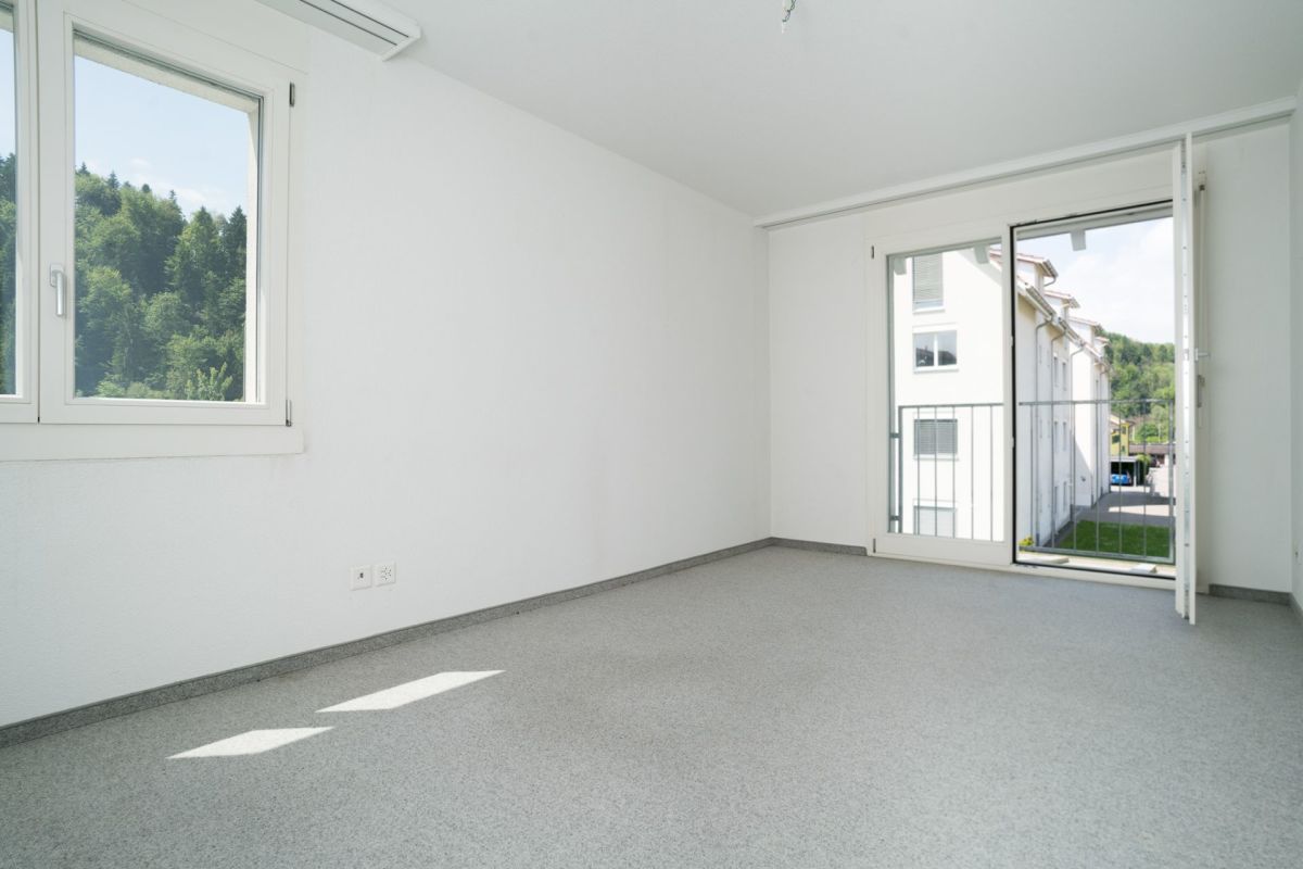 Heller leerer Raum mit Balkon und Blick ins Grüne