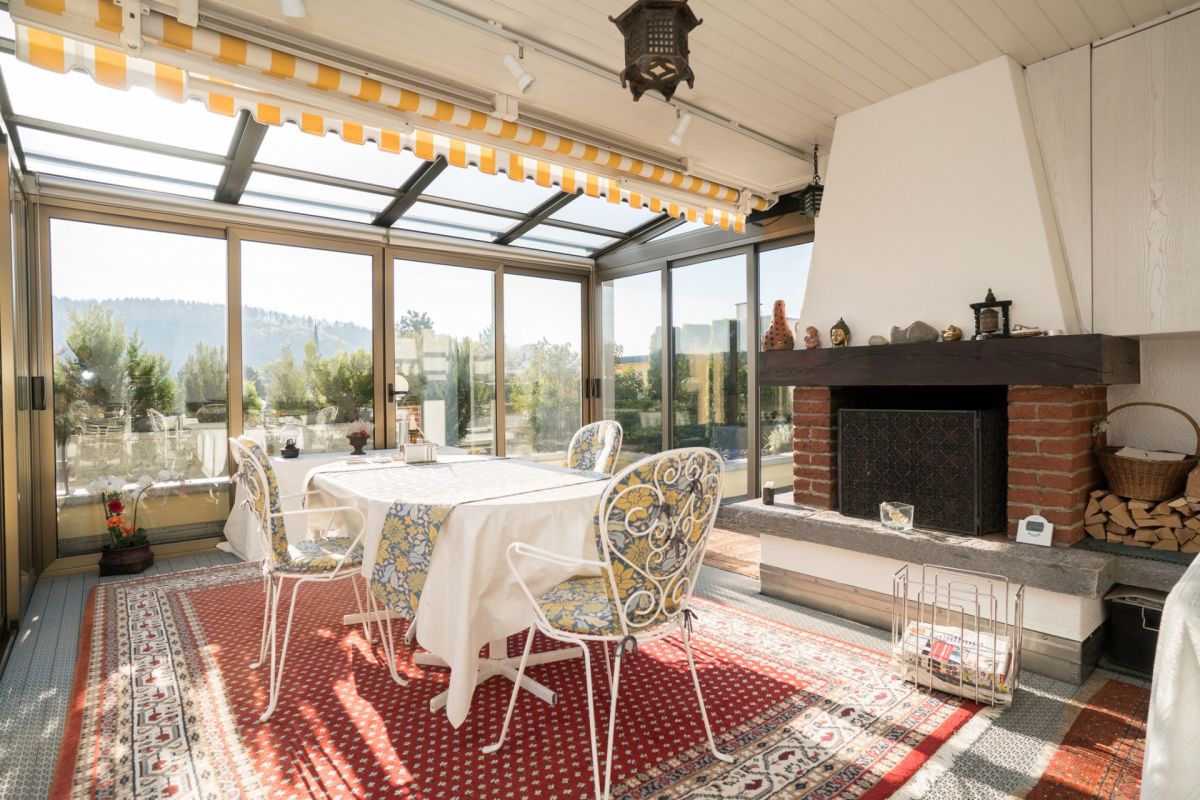 Verglaster Wintergarten mit Kamin und Esstisch