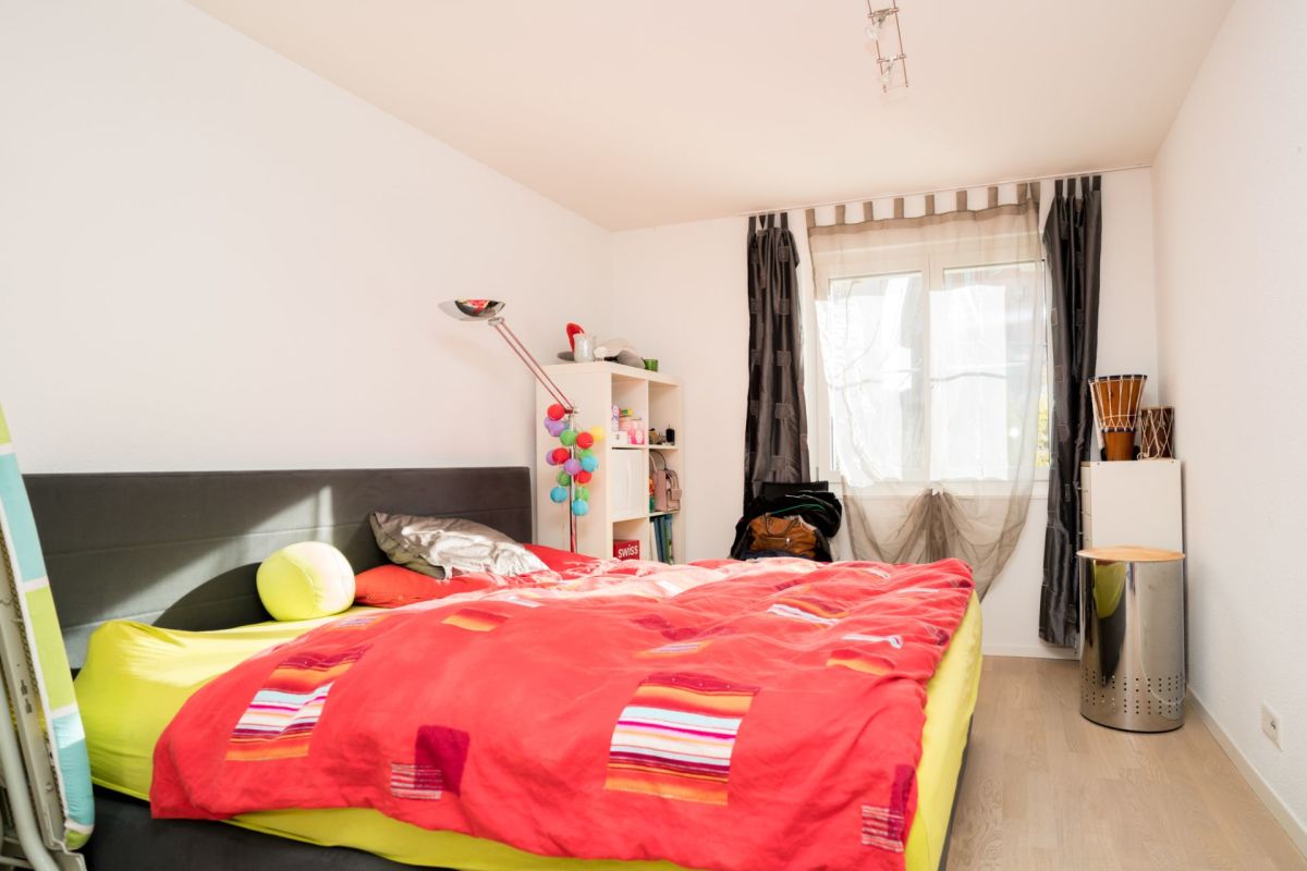 Helles Schlafzimmer mit farbigem Bett und Fenster