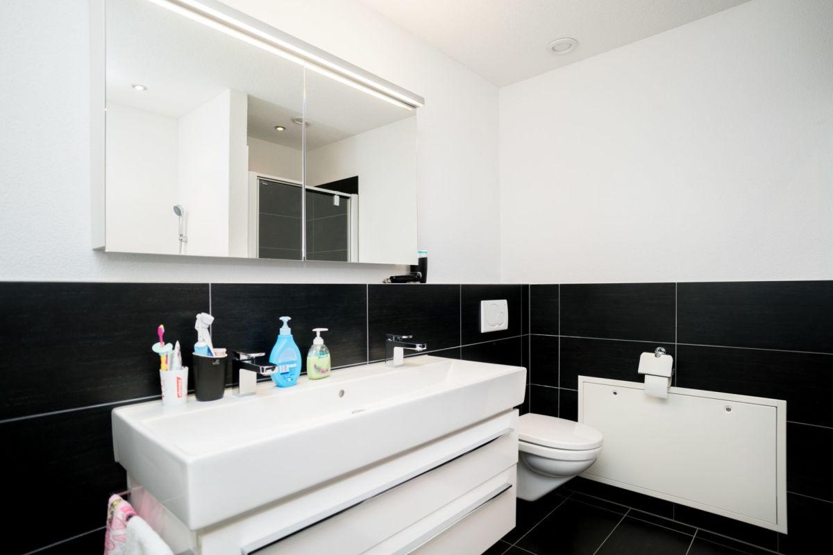 Modernes Gäste-WC mit schwarzen Fliesen und weißem Waschtisch