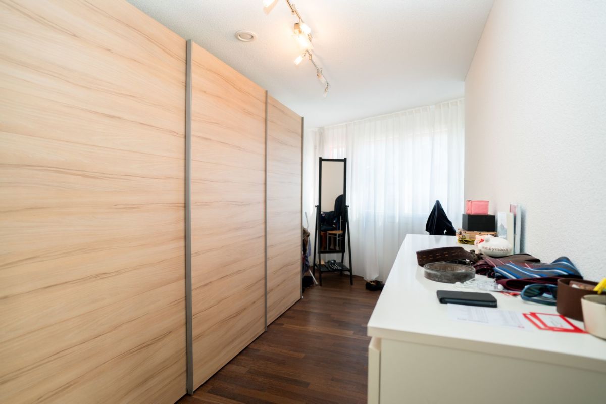 Schmaler Ankleide- oder Schlafzimmerbereich mit Einbauschrank und Tisch