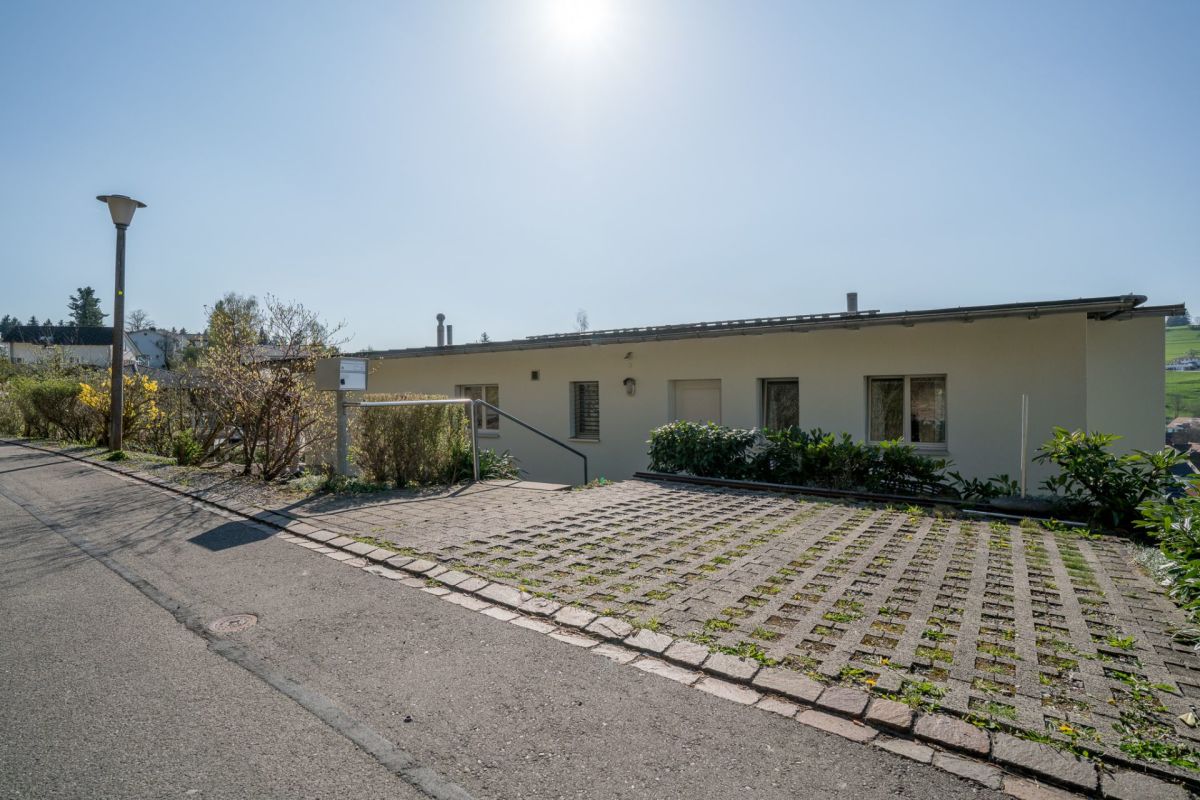 Außenansicht eines eingeschossigen Wohnhauses mit Zufahrt