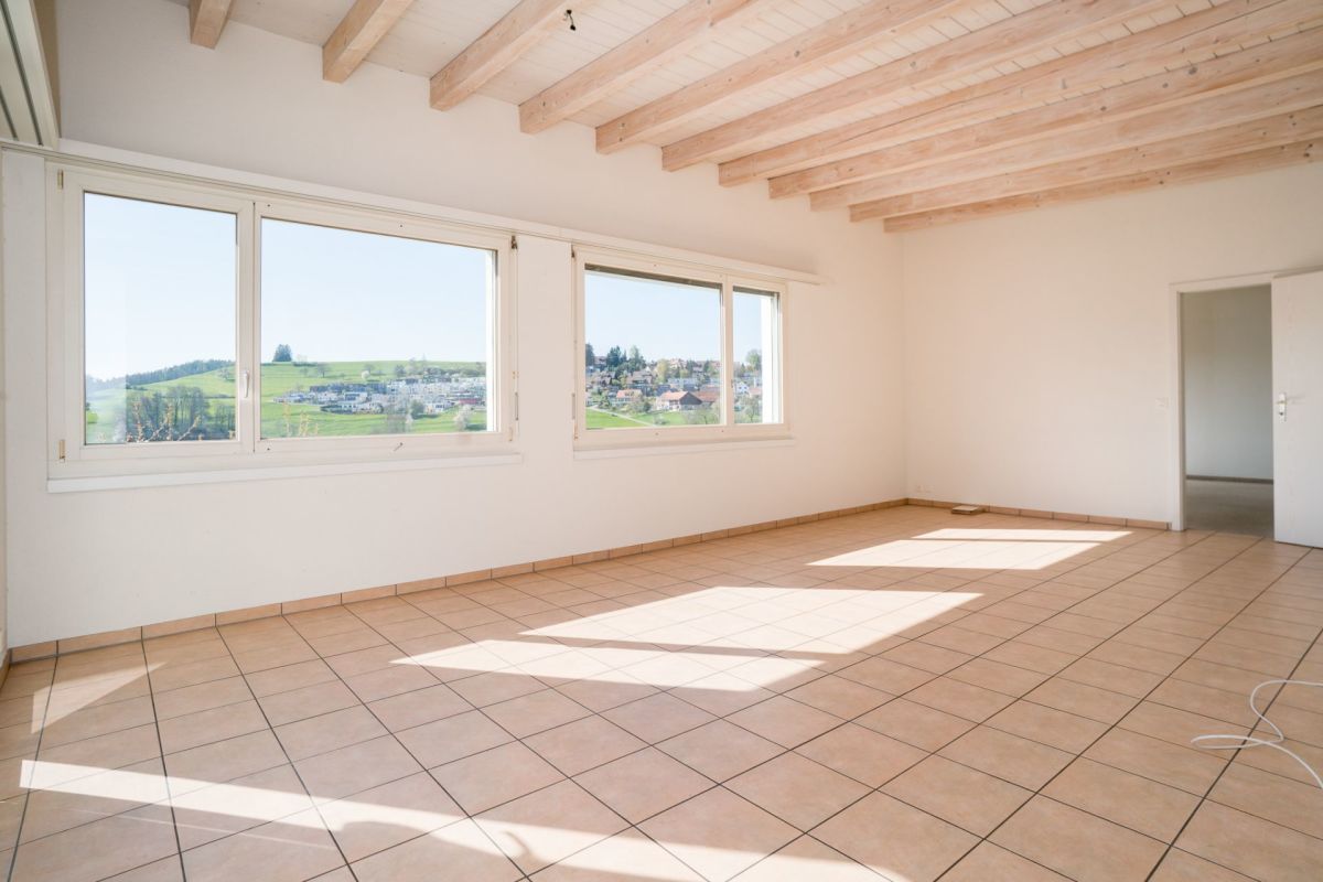 Heller leerer Raum mit Fliesenboden und Holzdeckenbalken