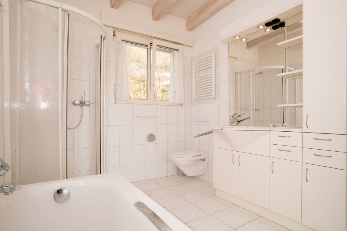 Helles Badezimmer mit Badewanne, Dusche und Fenster