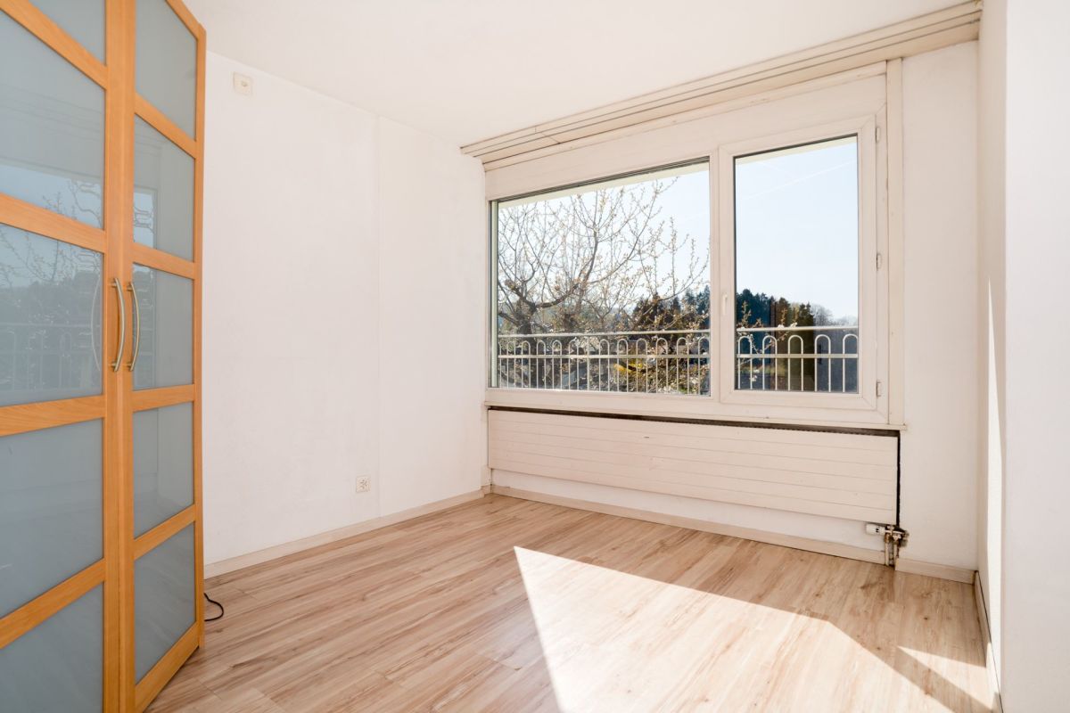 Heller leerer Raum mit großem Fenster und Einbauschrank