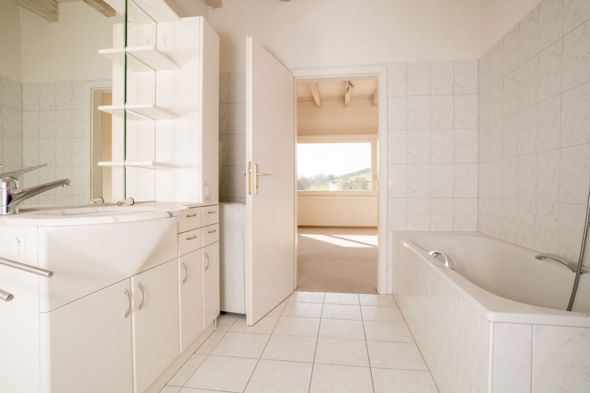 Helles Badezimmer mit Wanne und Blick ins Grüne