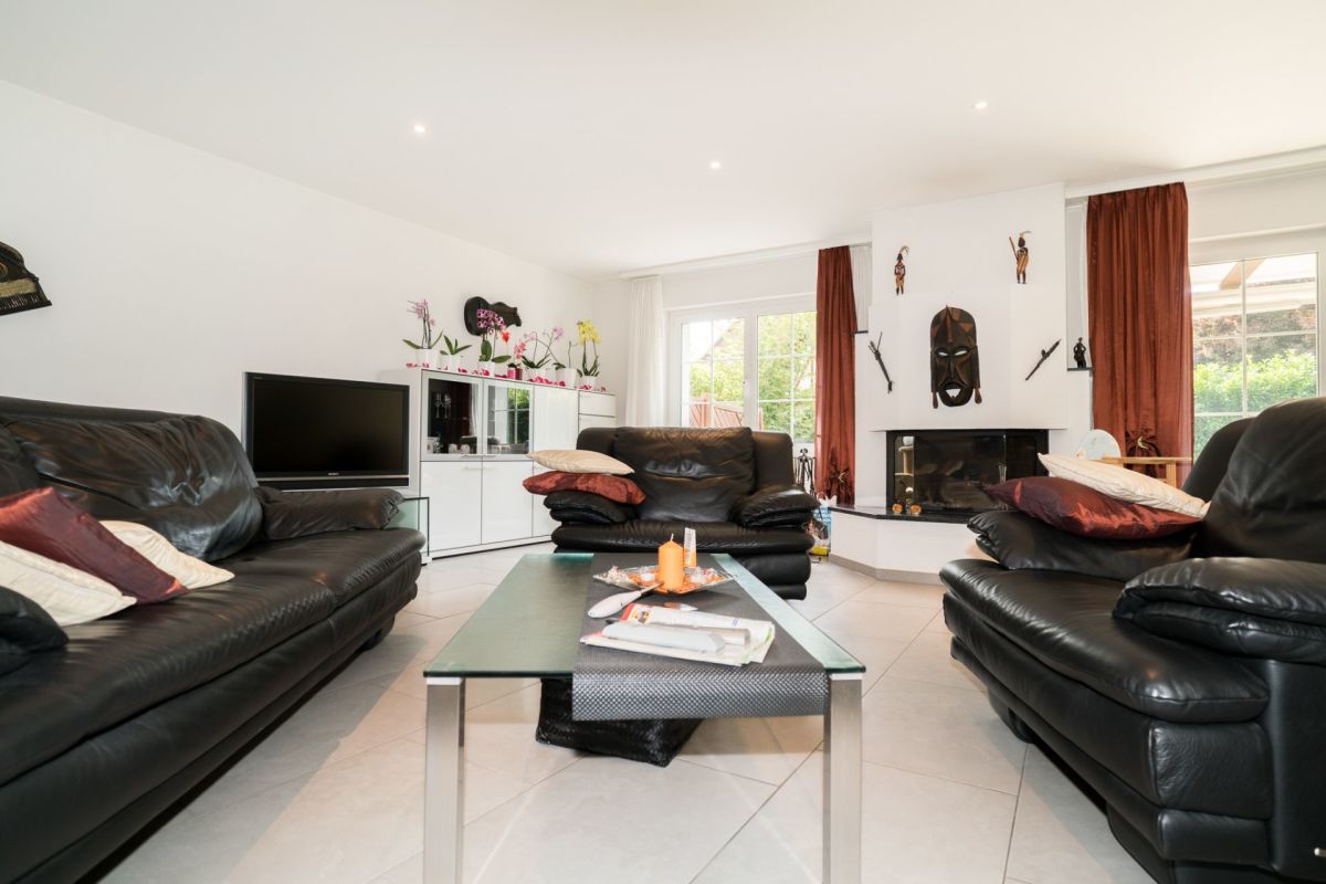 Helles Wohnzimmer mit Kamin und schwarzen Ledersofas